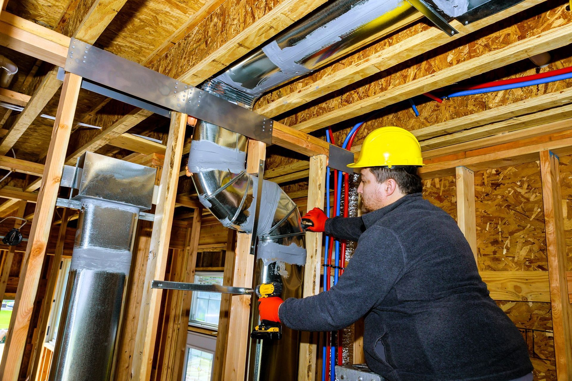 Professional in a hard hat installing ductwork in a residential home