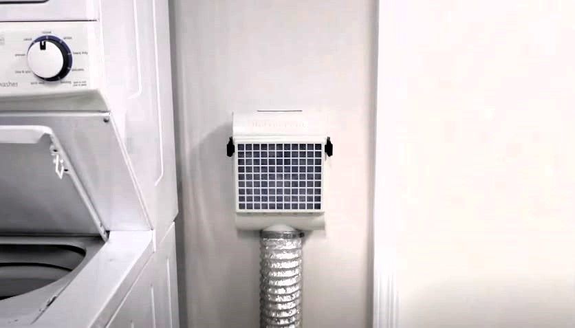 Laundry room with a washing machine and wall-mounted dryer vent kit.