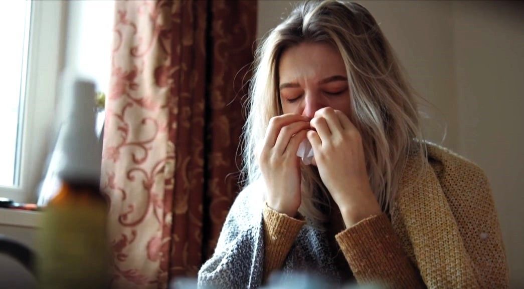 Woman sneezing due to poor indoor air quality at home