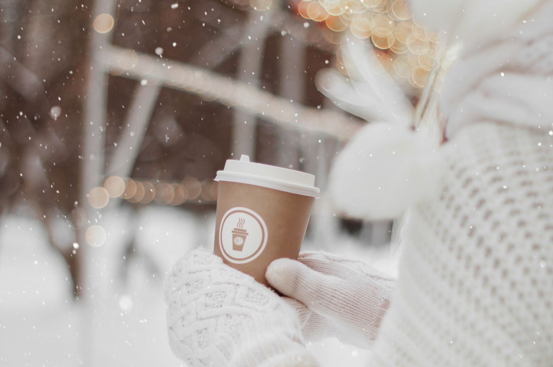 woman with gloves holds coffee cup in the snow