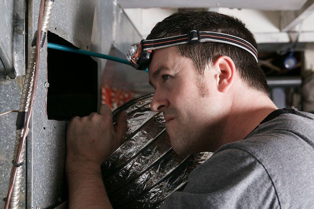 duct cleaning technician peers into duct to be cleaned