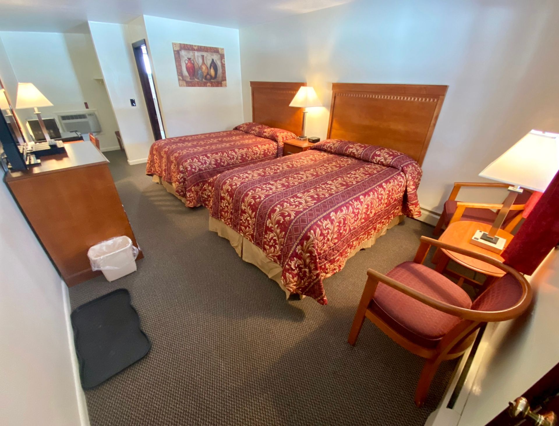 A hotel room with two beds , a chair and a dresser.