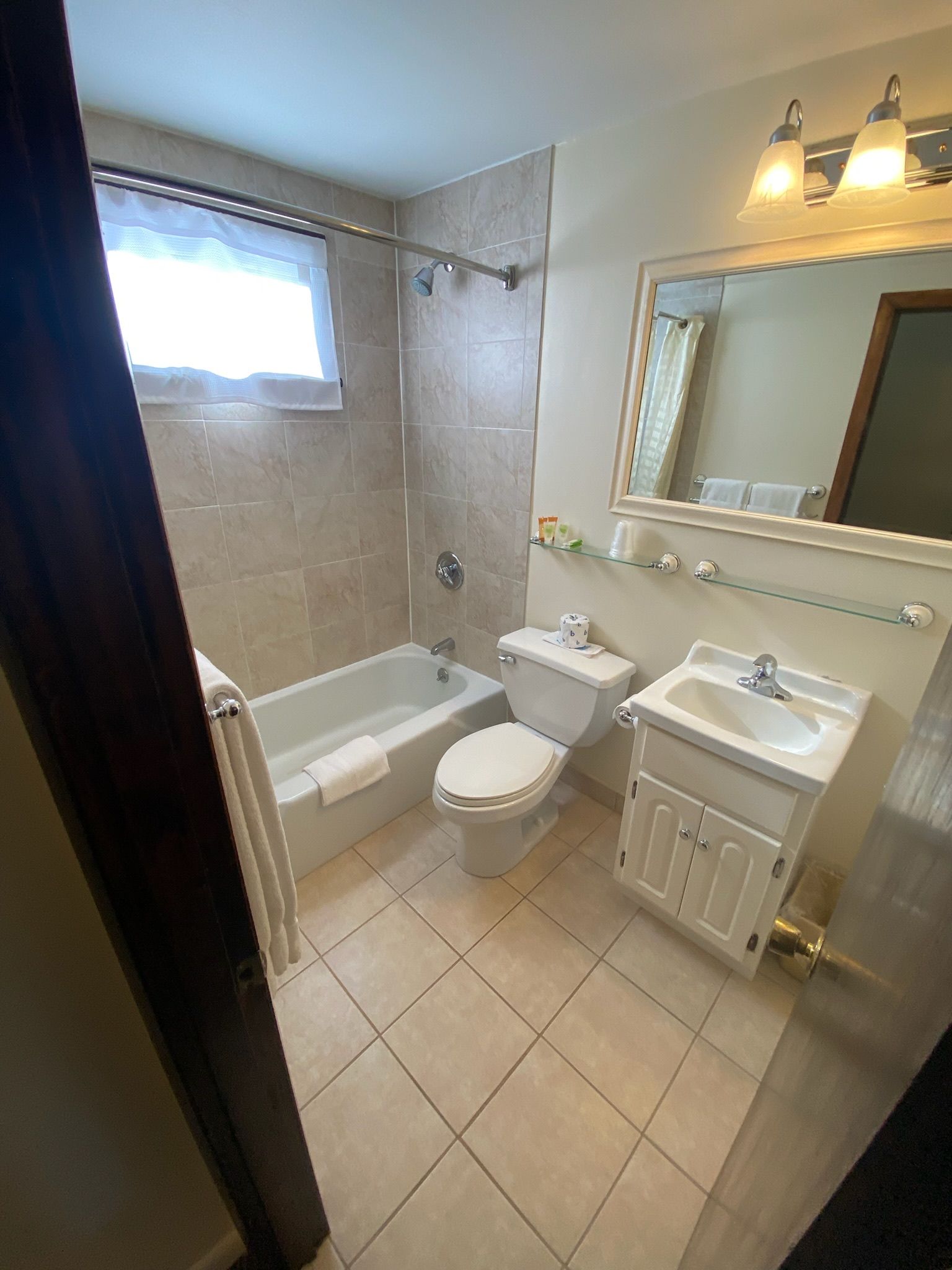 A bathroom with a tub , toilet , sink and mirror.