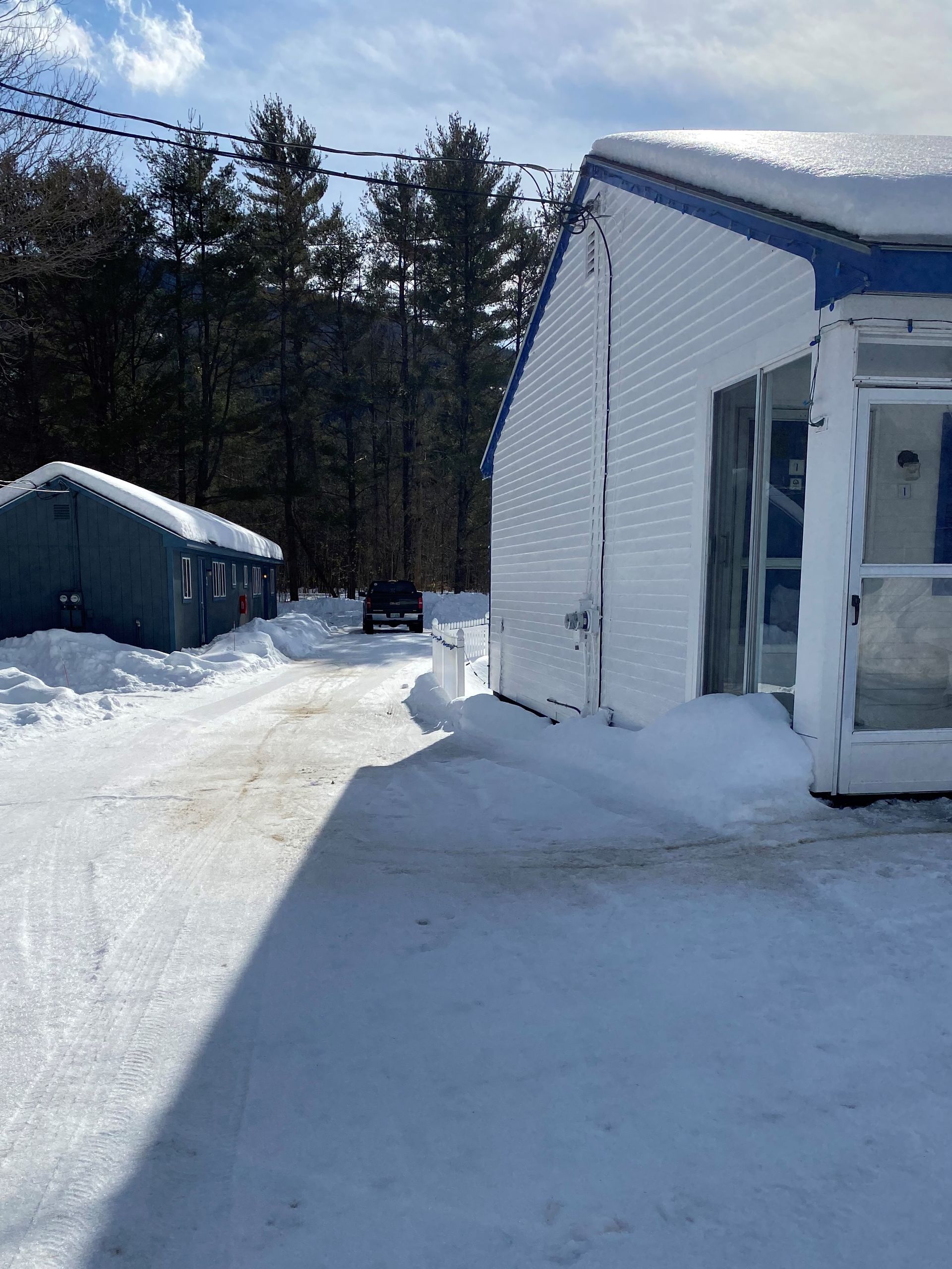 A white building with a blue trim is covered in snow
