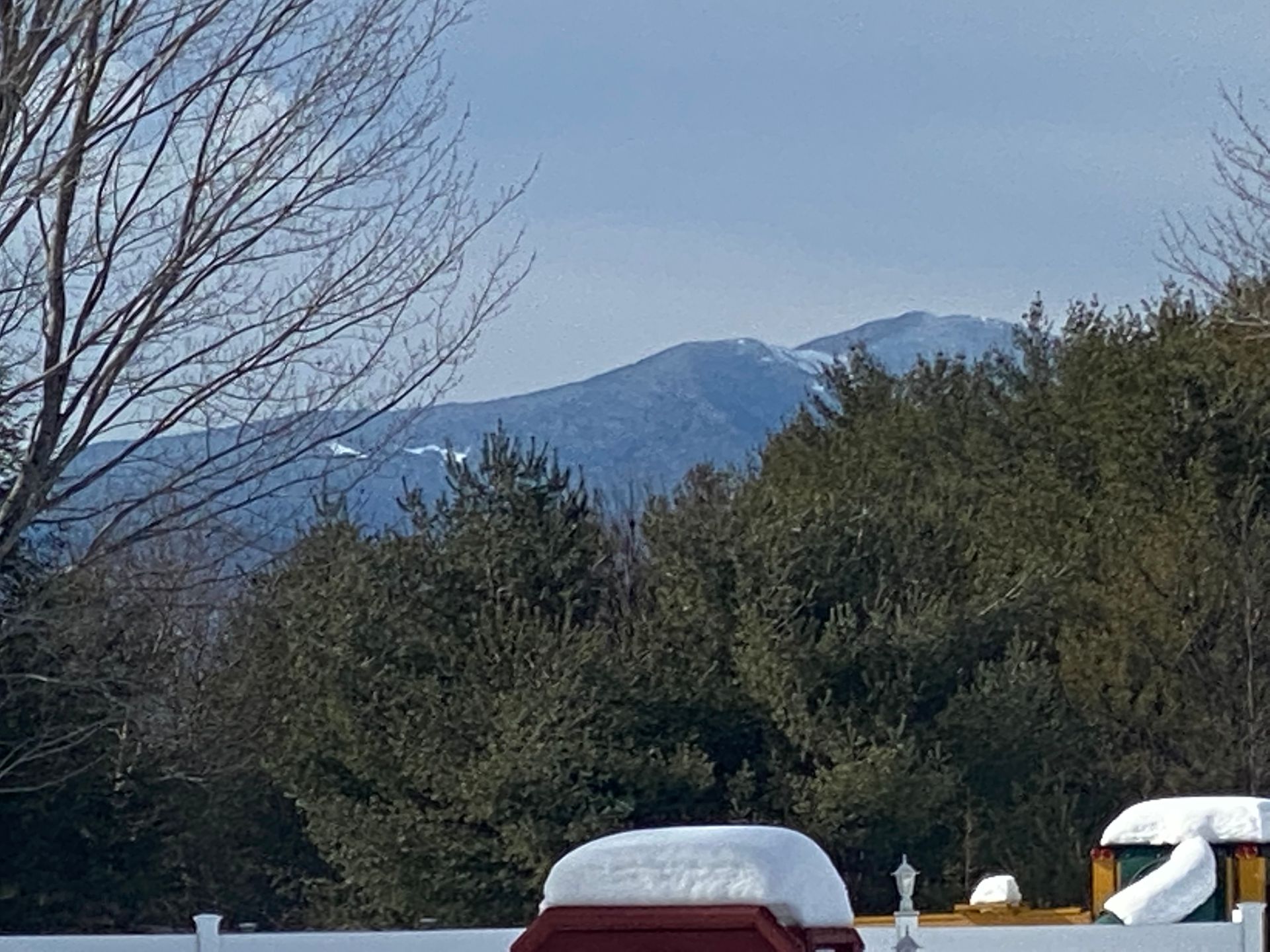 A snowy landscape with mountains in the background and trees in the foreground