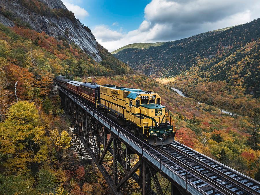 A train is going over a bridge in the mountains.
