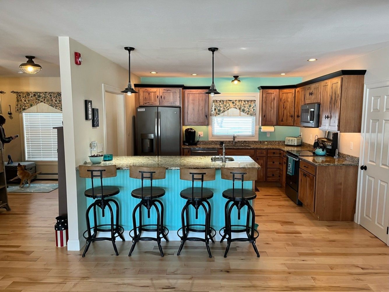 A kitchen with a blue island , stools and a refrigerator.