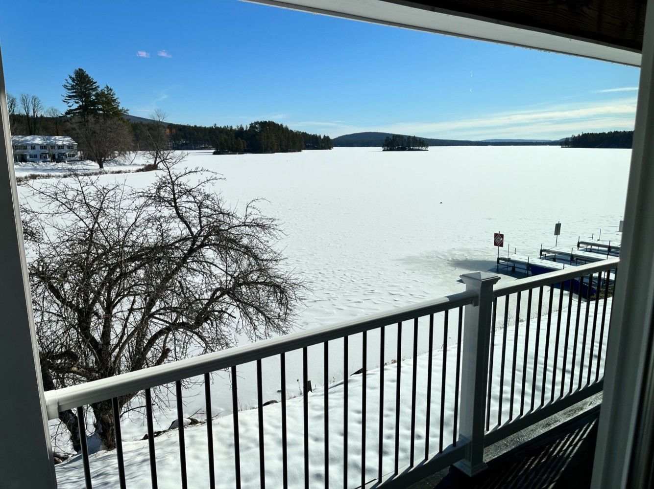 A view of a lake from a balcony with snow on the ground