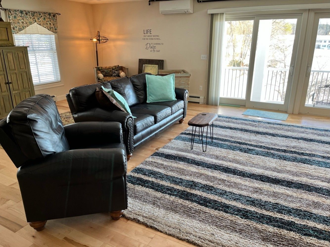 A living room with a couch , chair , rug and sliding glass doors.