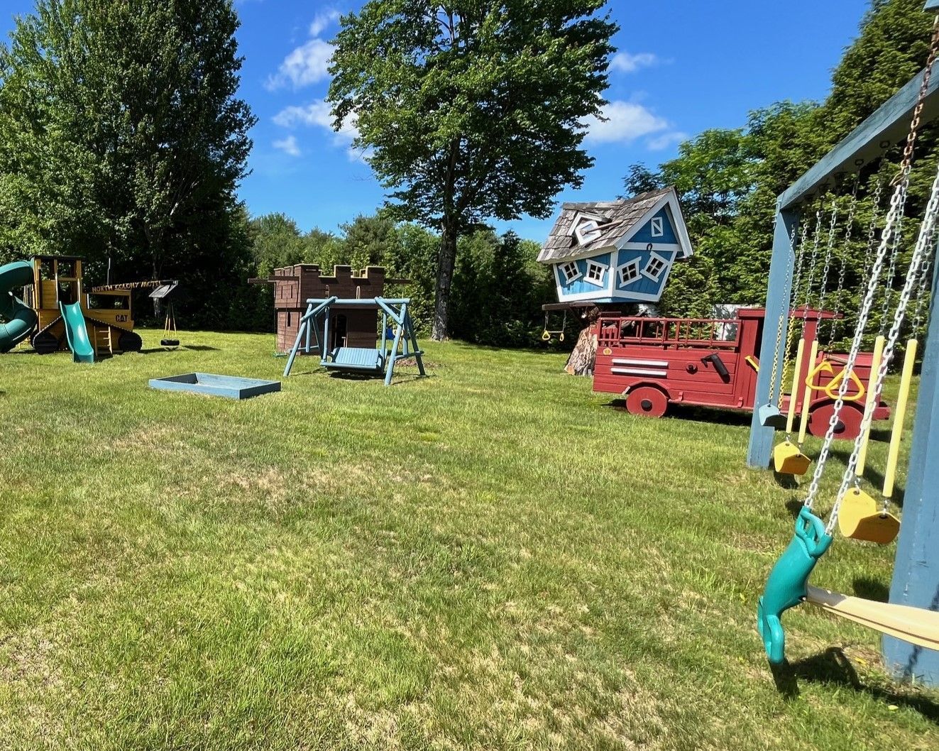 A playground with a slide , swings , and a fire truck.