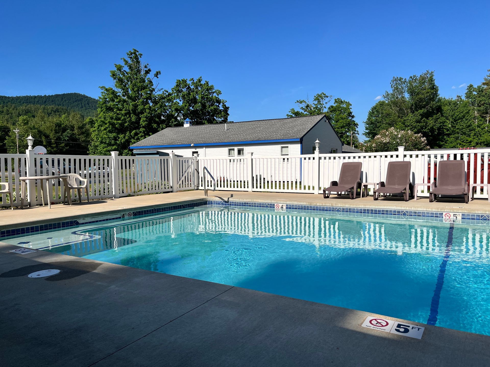 A large swimming pool with chairs and tables around it