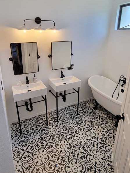 A bathroom with two sinks , two mirrors and a bathtub.