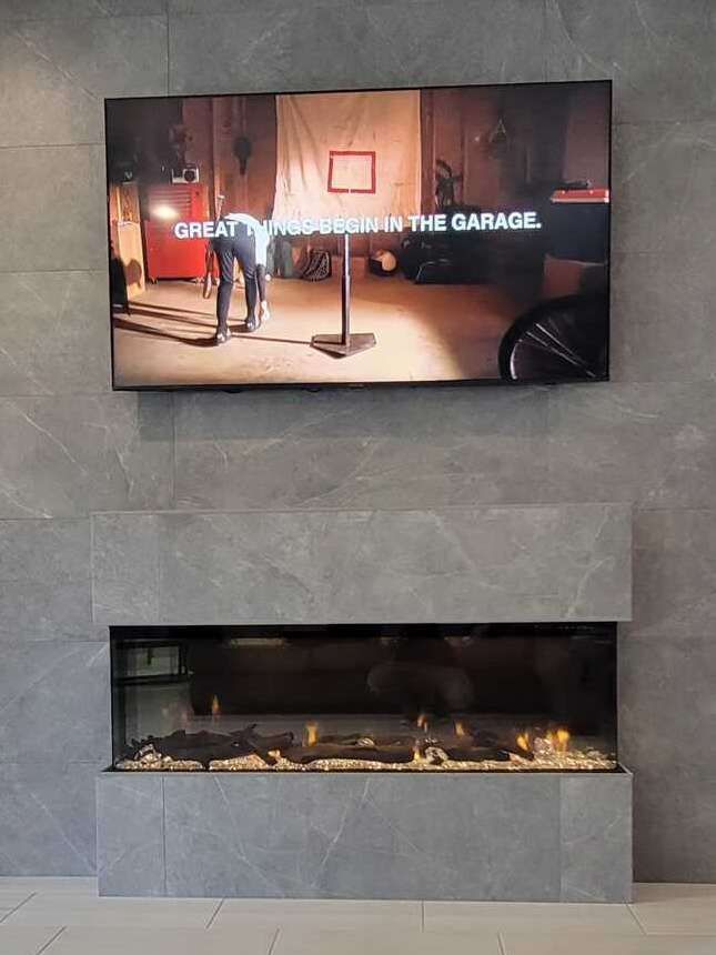 A flat screen tv is hanging on a wall above a fireplace.