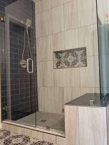 A bathroom with a walk in shower with a glass door.