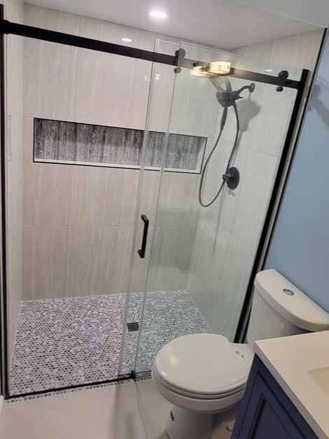 A bathroom with a toilet and a shower with a sliding glass door.