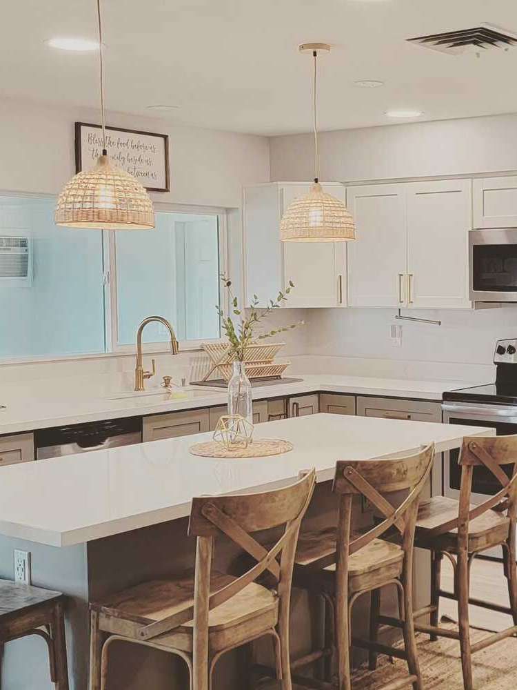 A kitchen with a large island , stools , a sink and a microwave.