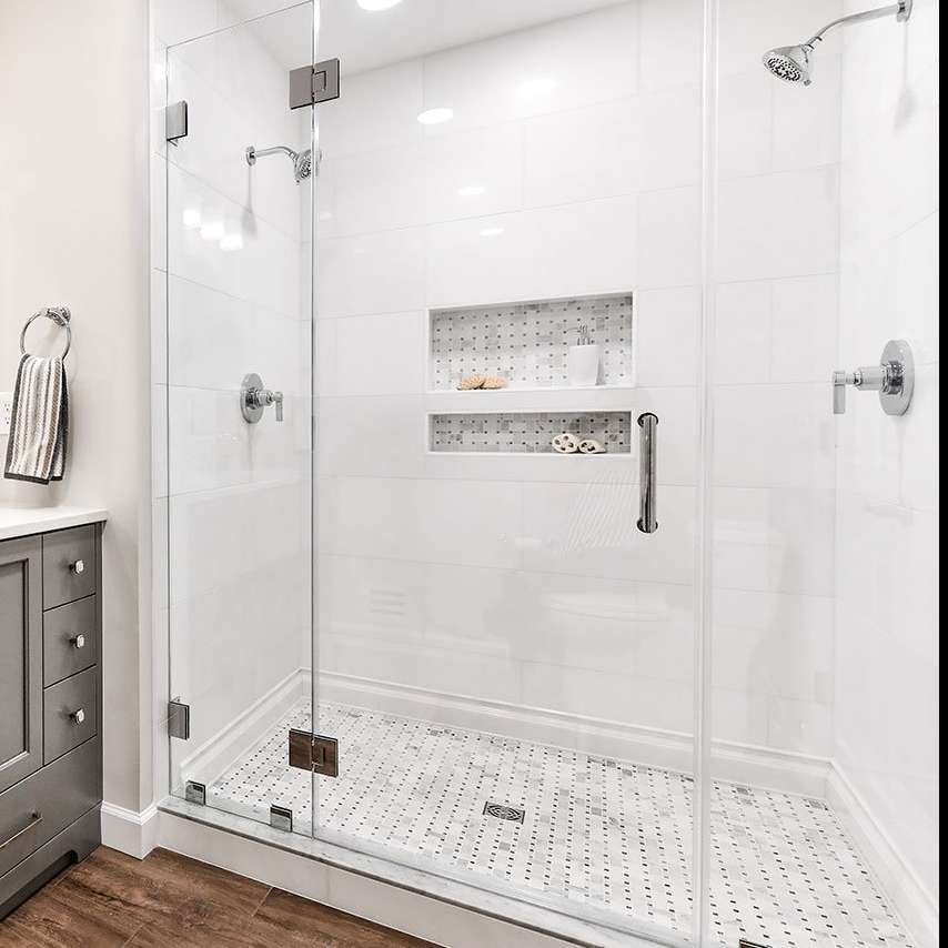 A bathroom with a walk in shower with a glass door.