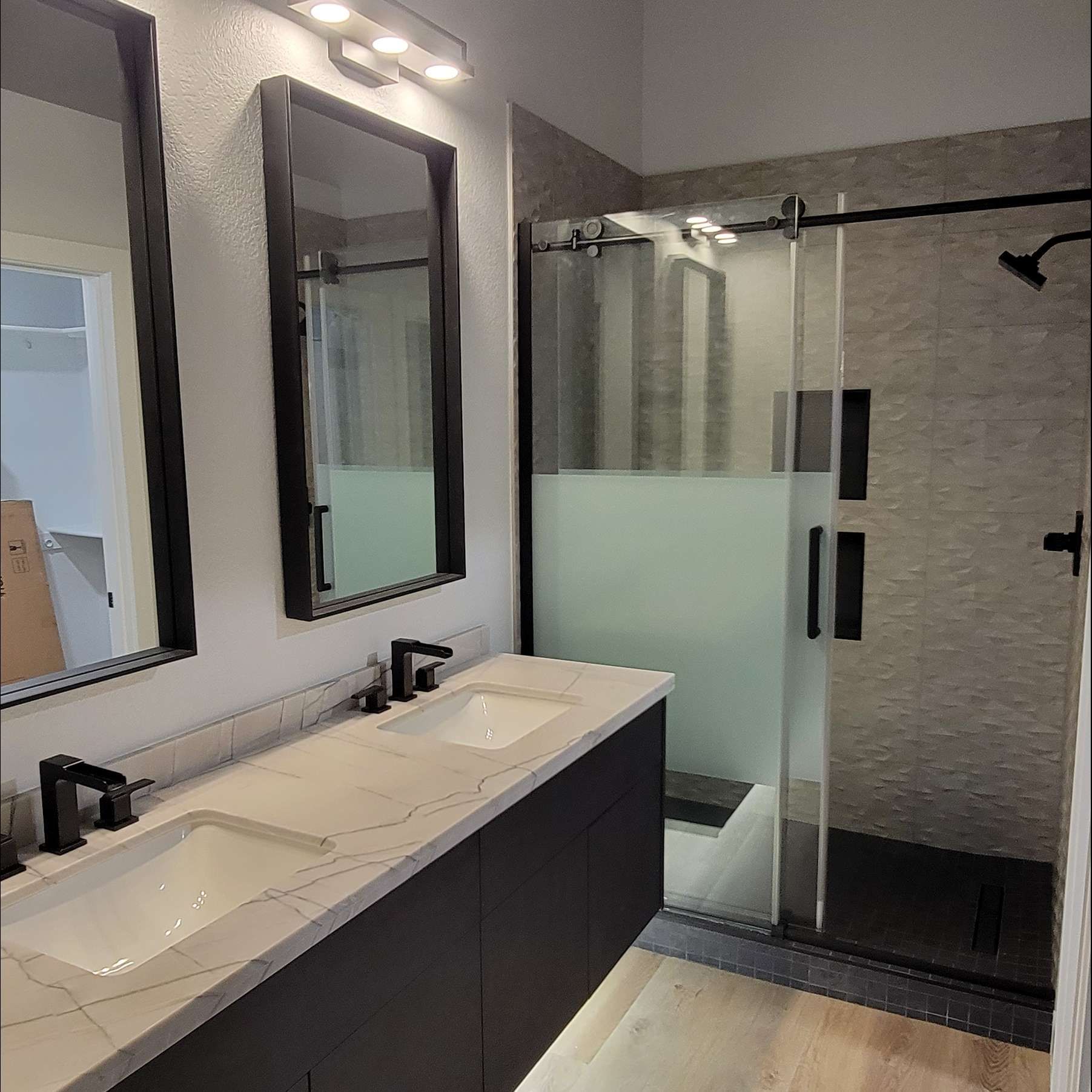 A bathroom with two sinks and a walk in shower.