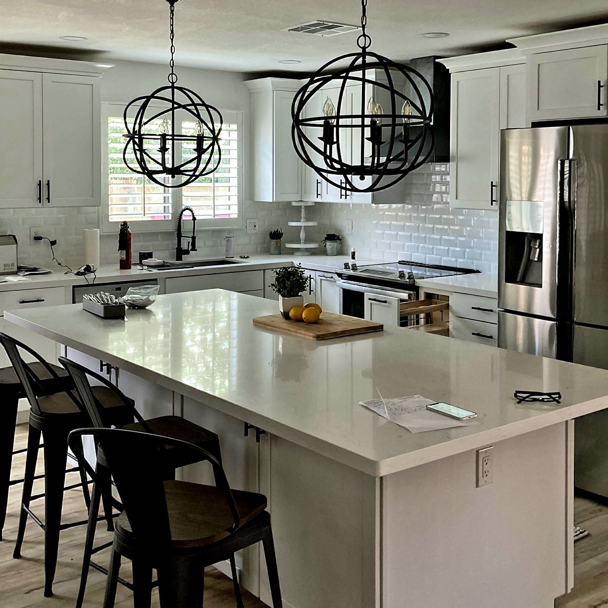 A kitchen with white cabinets, stainless steel appliances, and a large island.