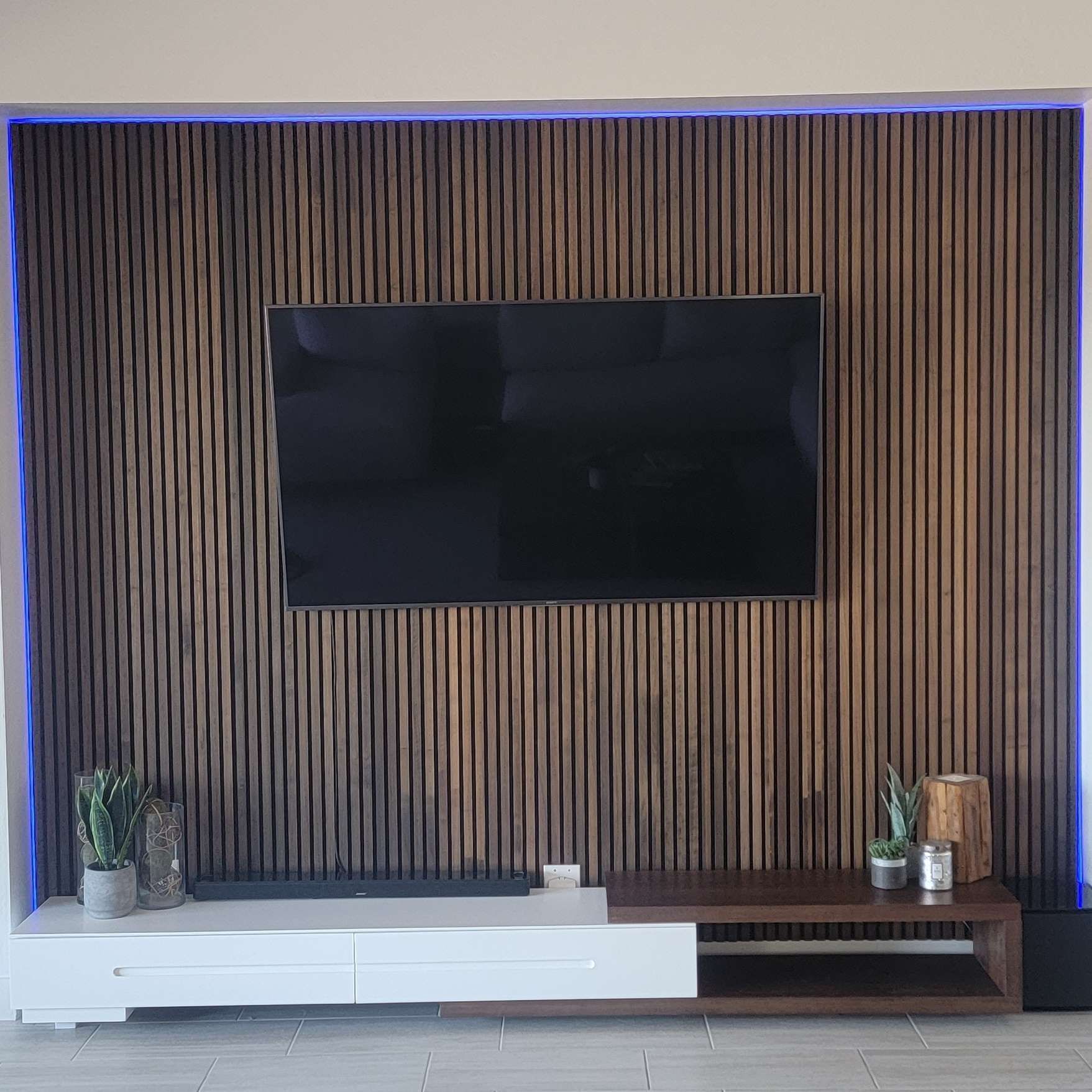 A living room with a wooden wall and a flat screen tv on the wall.