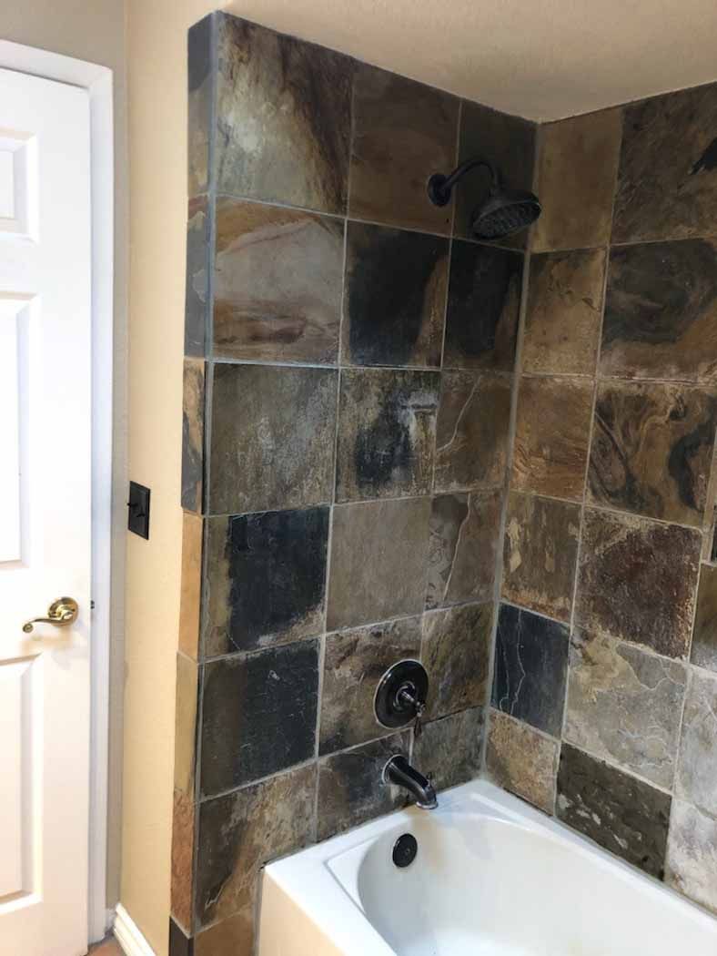 A bathroom with a bathtub , shower , and tiled walls.