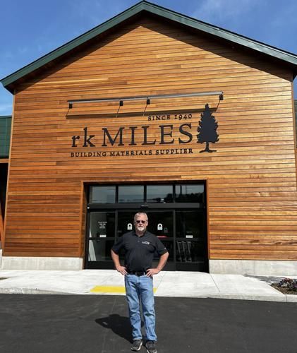 A man is standing in front of a building that says rk miles