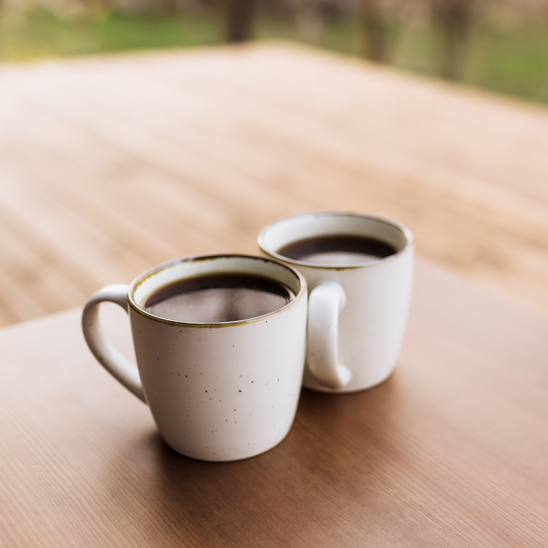 Two cups of coffee are sitting on a wooden table.