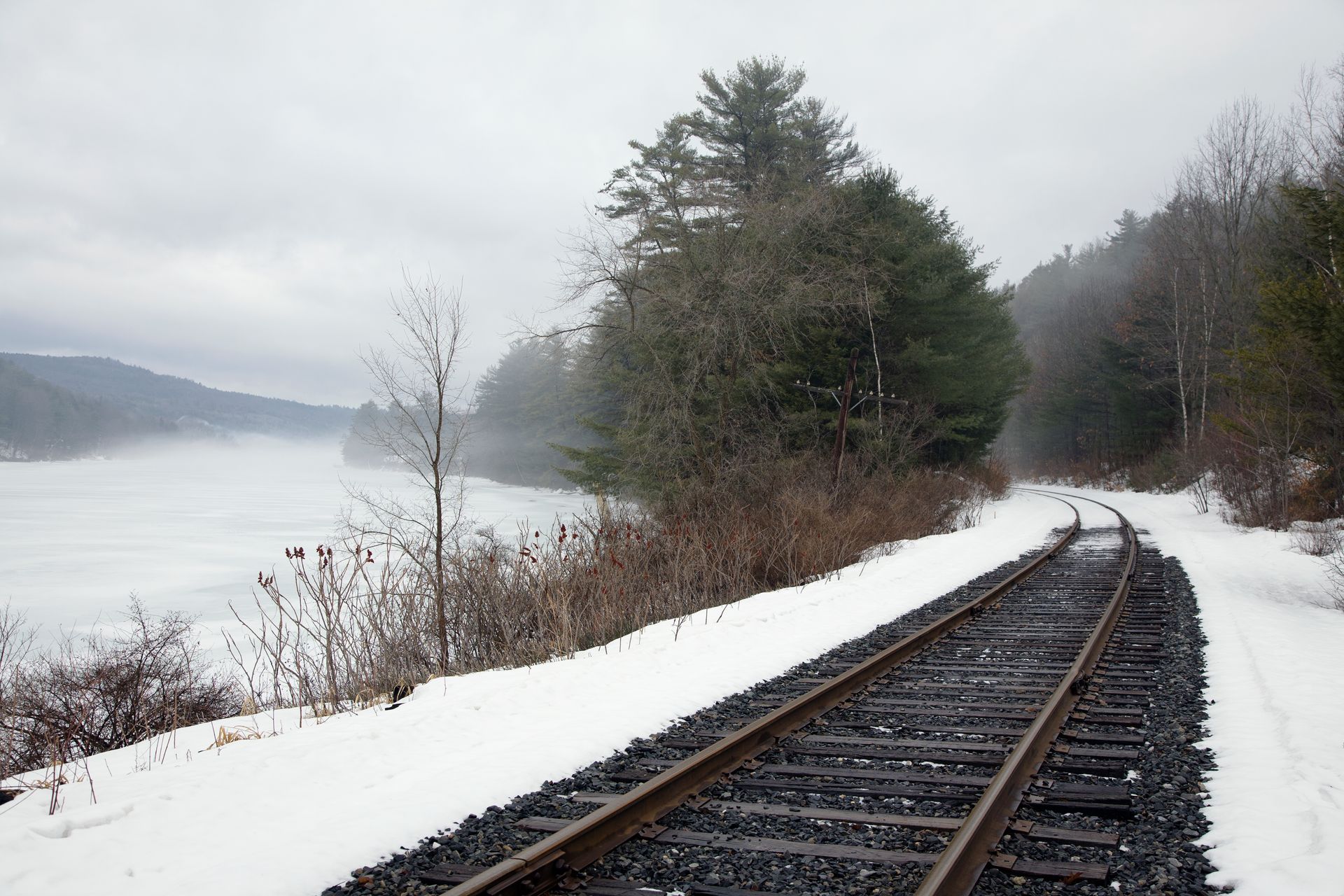 Train tracks in the snow with trees in the background