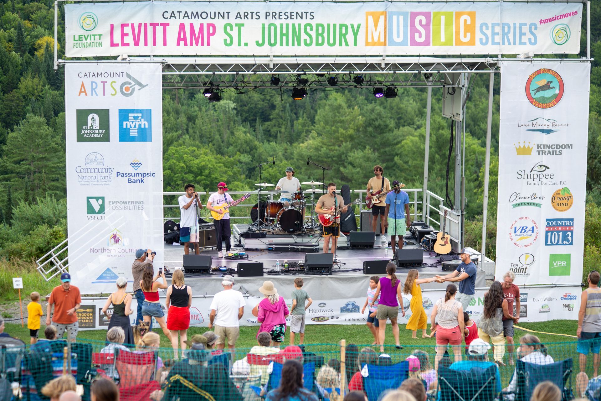 A group of people are standing in front of a stage at a music festival.