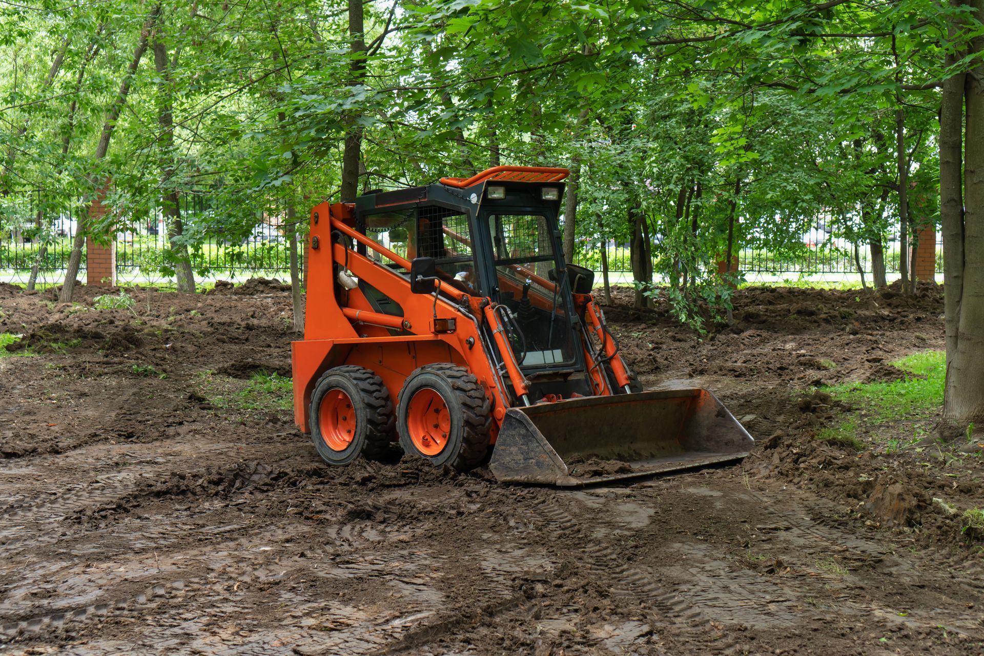 A small orange bulldozer is sitting in the middle of a muddy field.