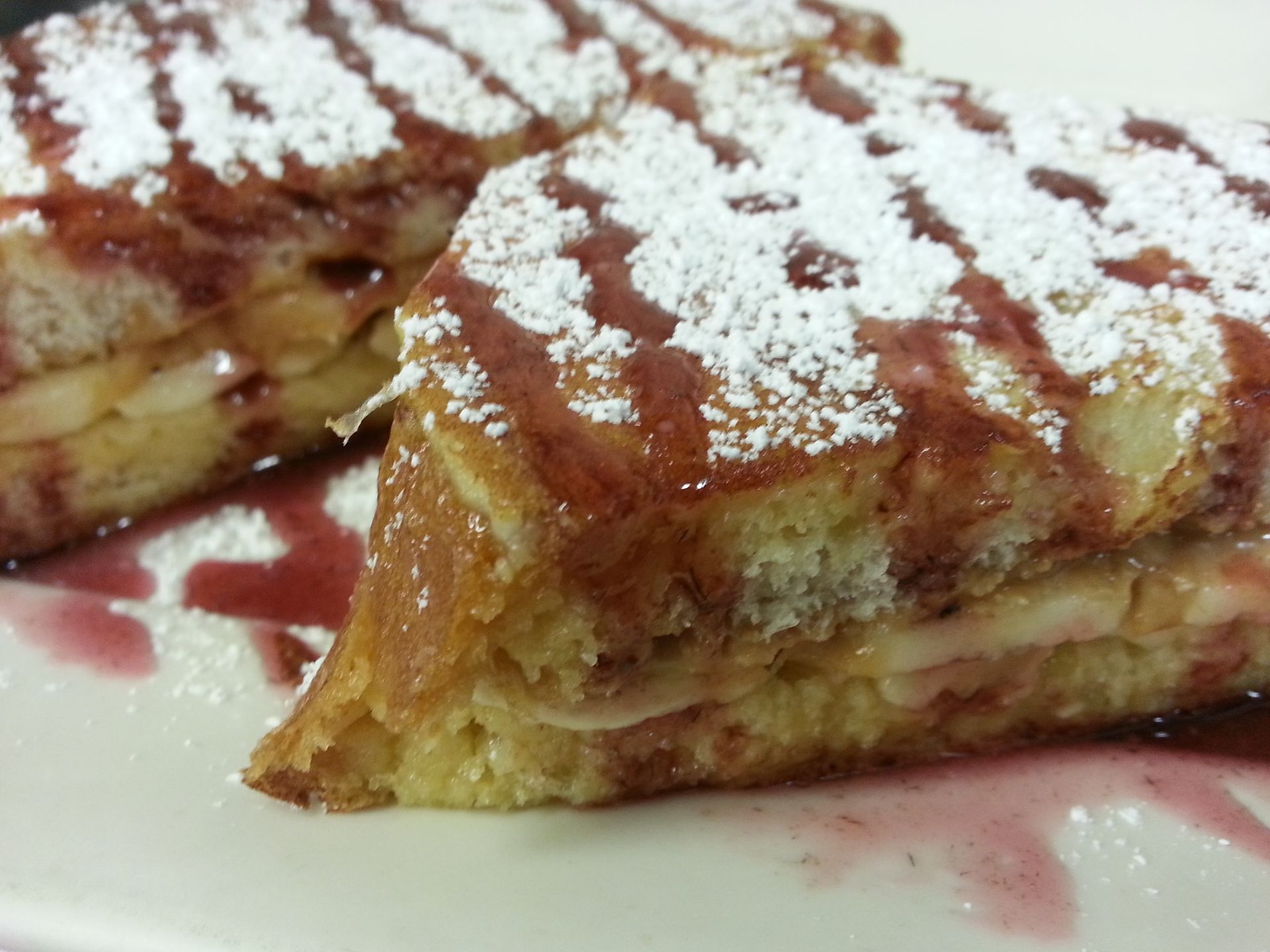 Two pieces of french toast with powdered sugar on a white plate