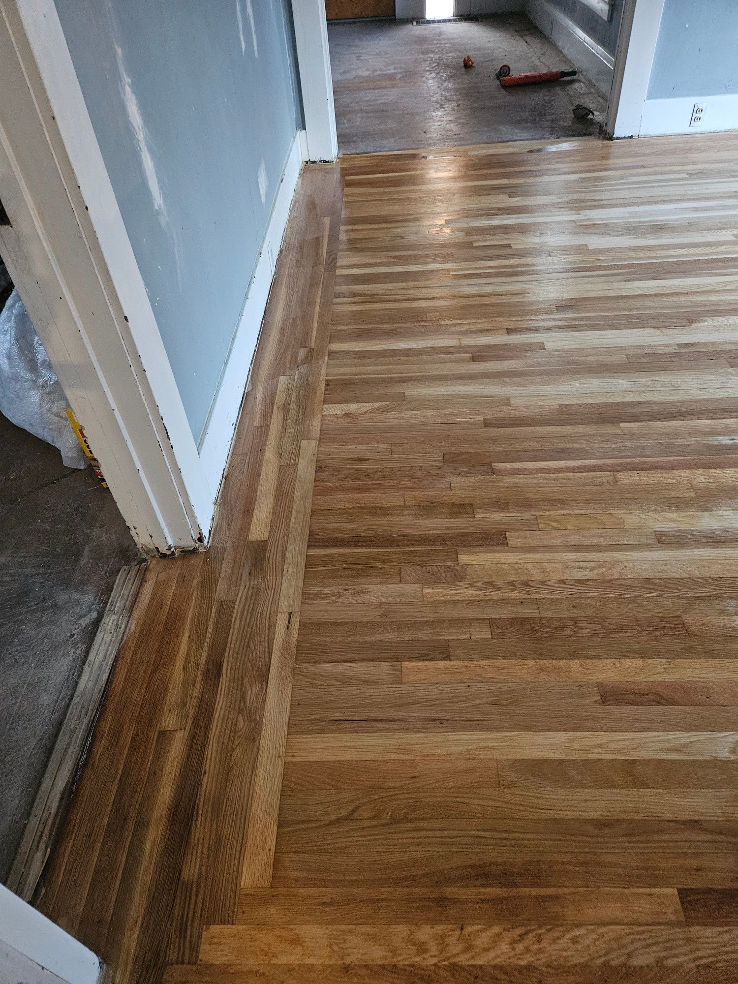 A wooden floor in a room next to a door.