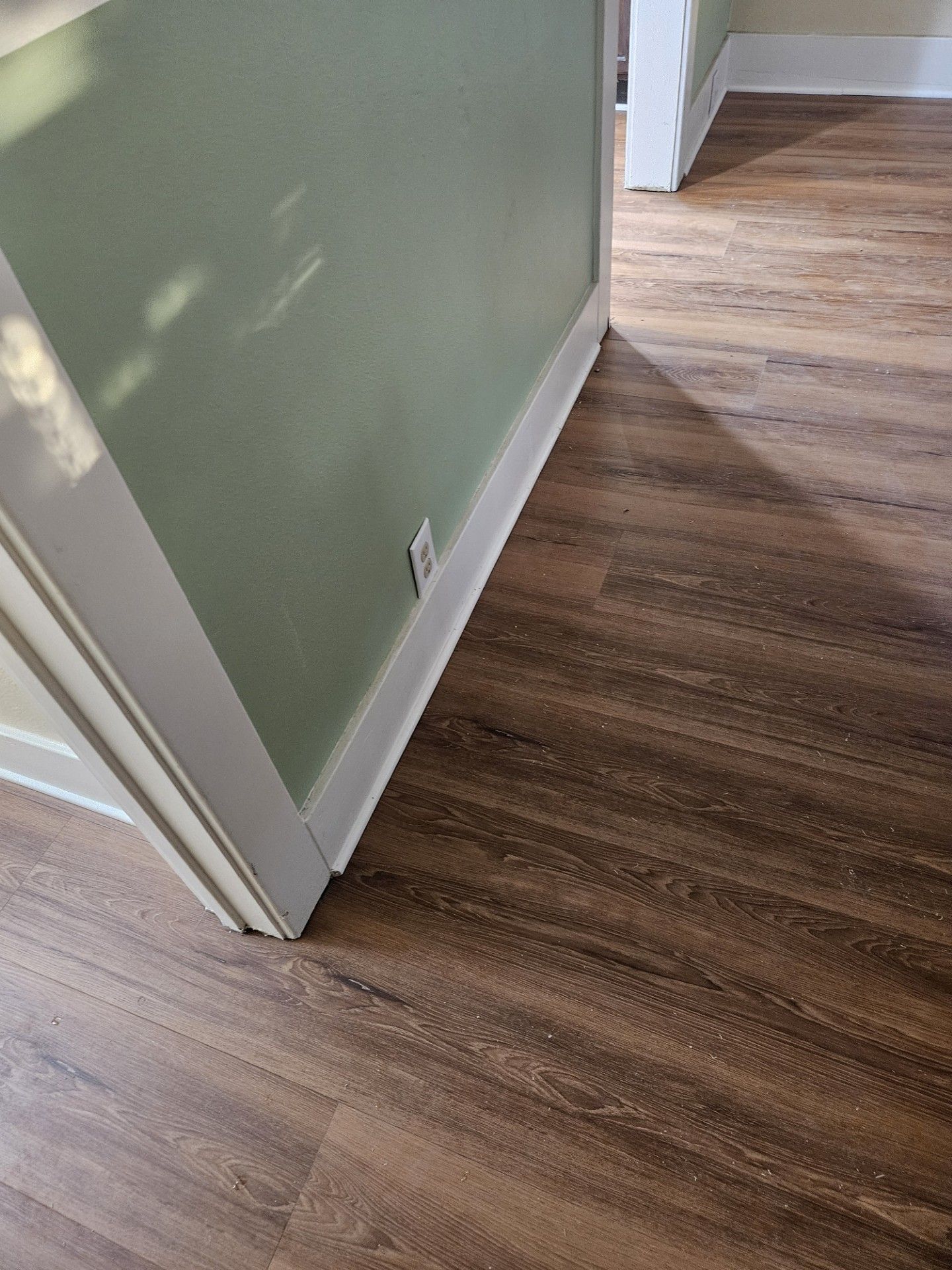 A wooden floor in a hallway next to a door.