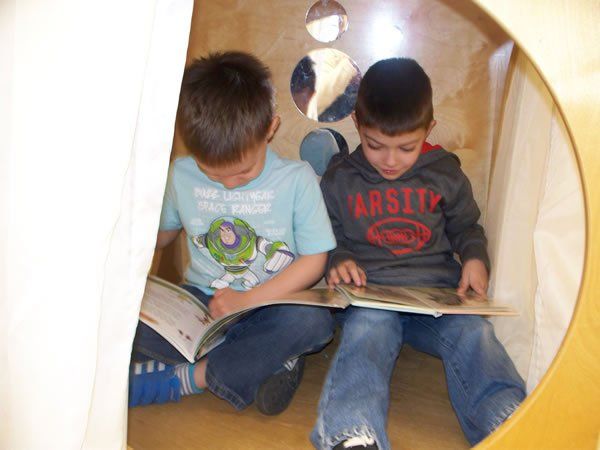 Two young boys are sitting in a circle reading books