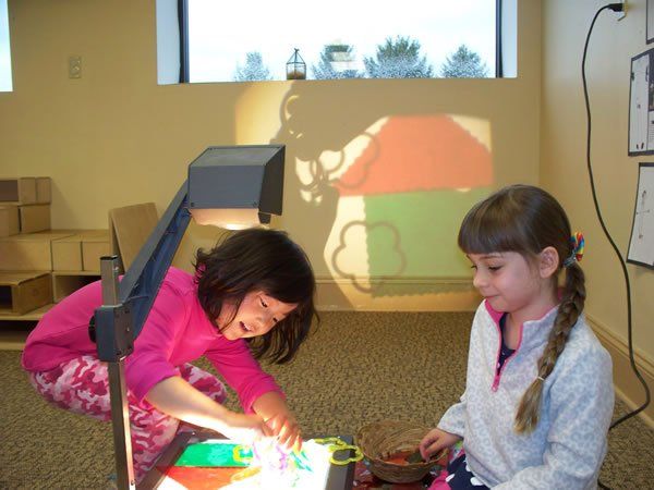 Two little girls are playing with a light box