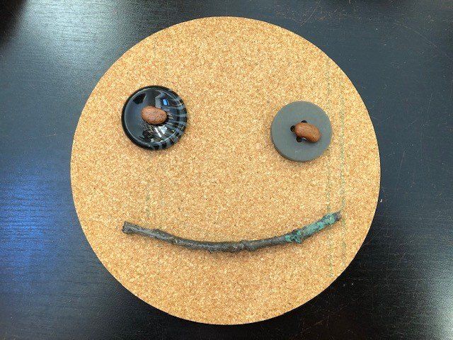 A smiley face made out of buttons and a stick