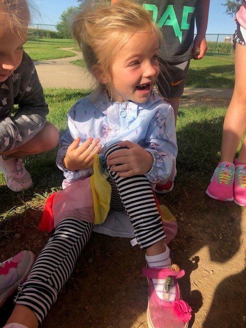 A little girl wearing a shirt that says dad is sitting on the ground