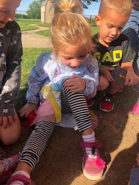 A little girl is sitting on the ground with a group of children.