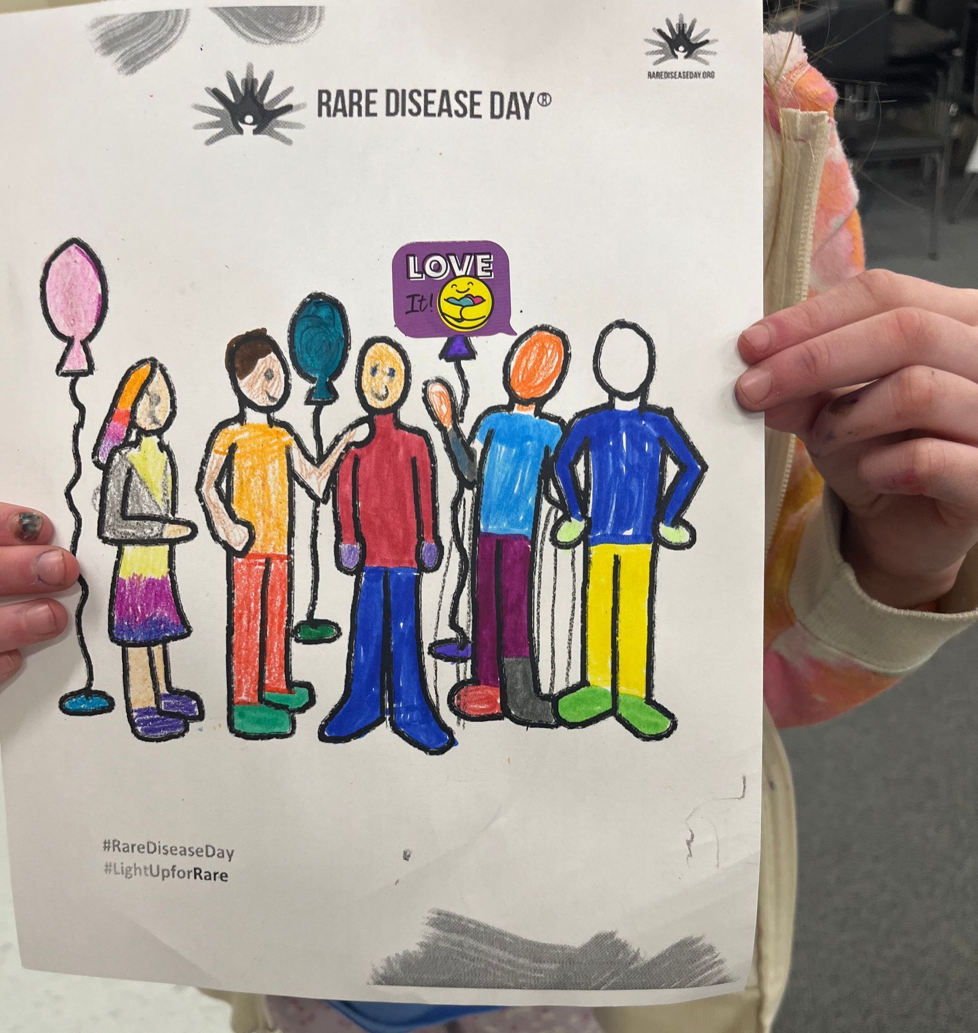A child is holding up a drawing for rare disease day