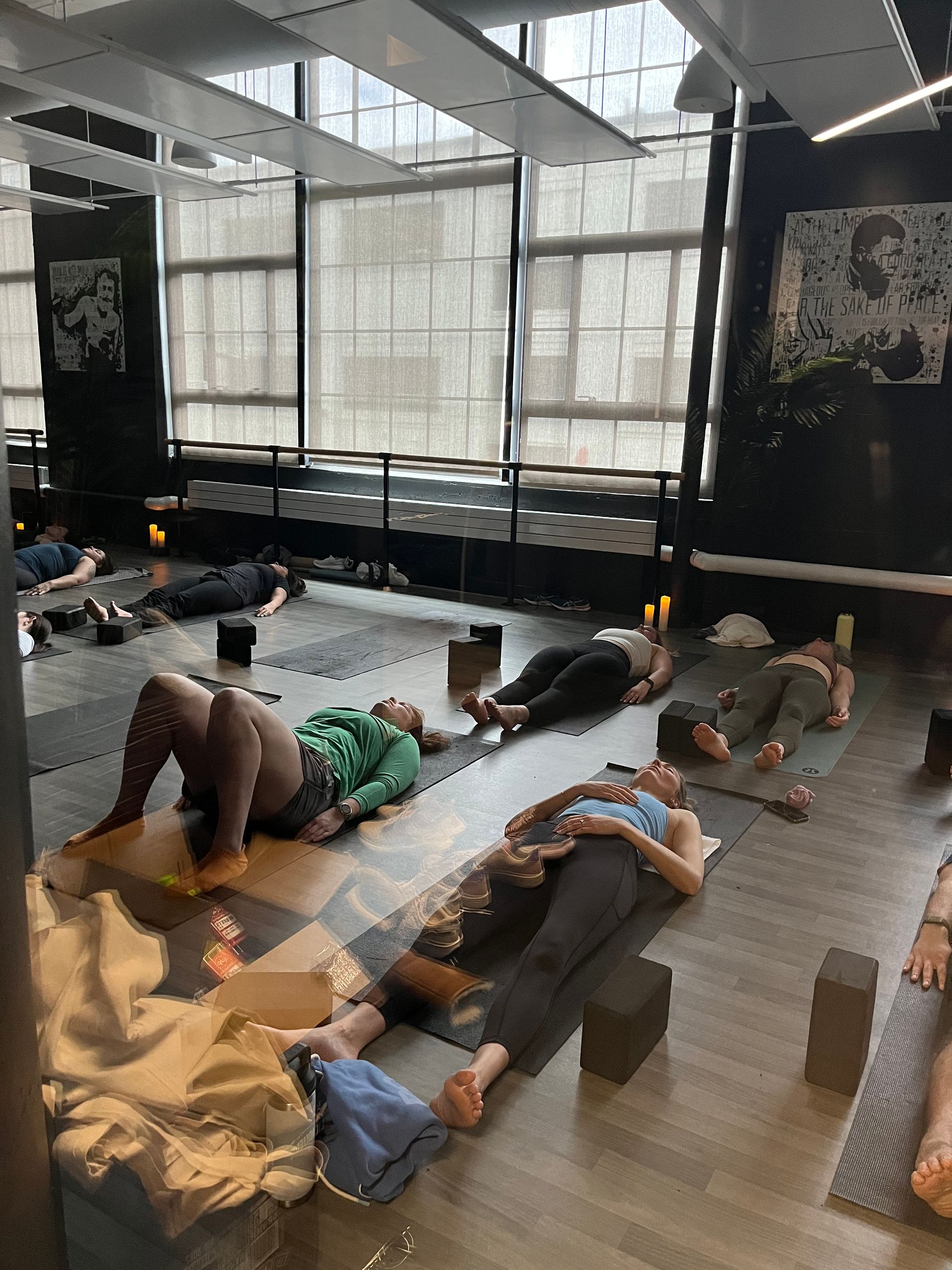 A group of people are laying on yoga mats in a gym for a yoga fundraiser for Serenely Guided Foundation.