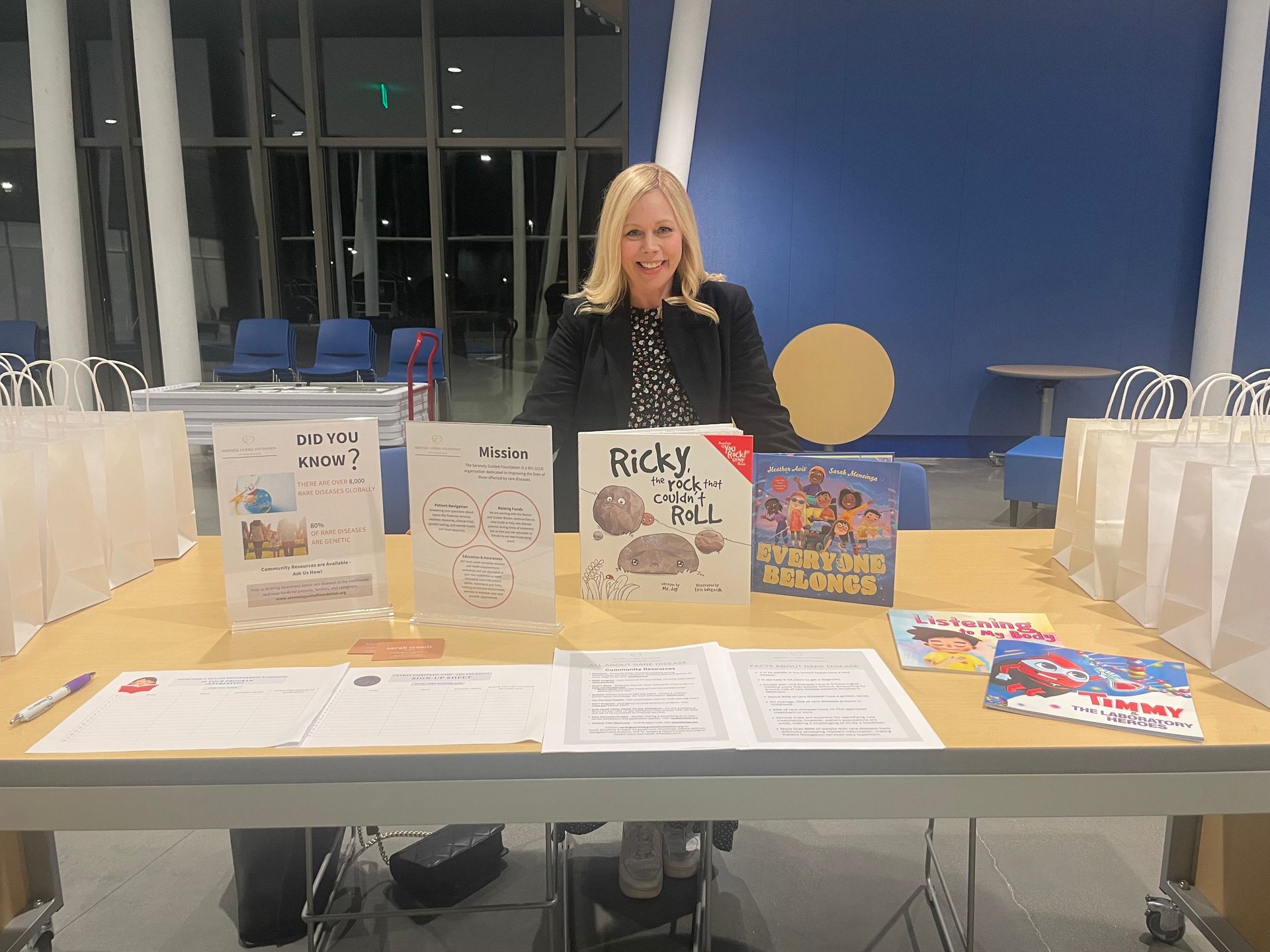 A woman is sitting at a table with books on it.