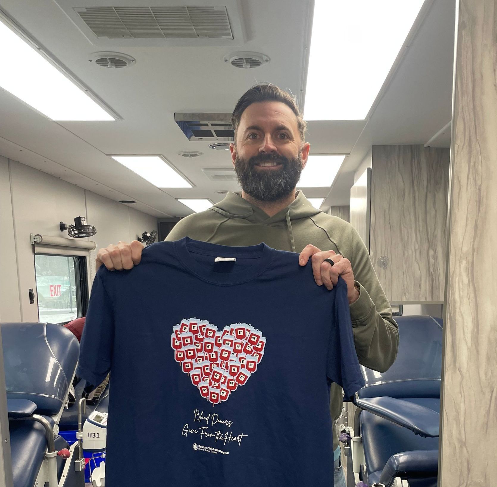 A man is holding a blue shirt with a heart on it