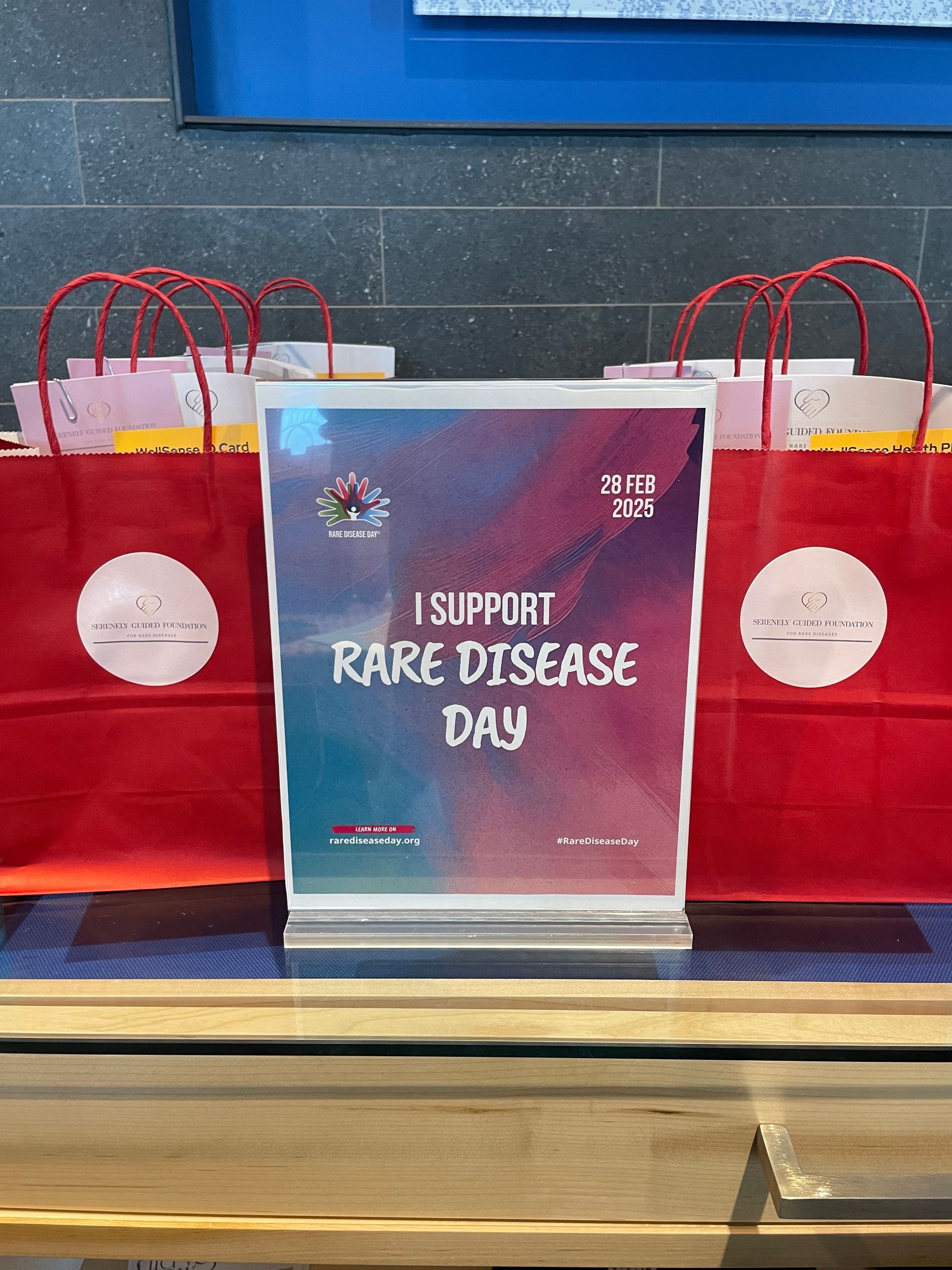 A table with red bags and a sign that says `` i support rare disease day ''