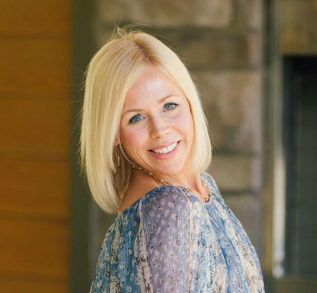 A woman in a blue dress is smiling for the camera.