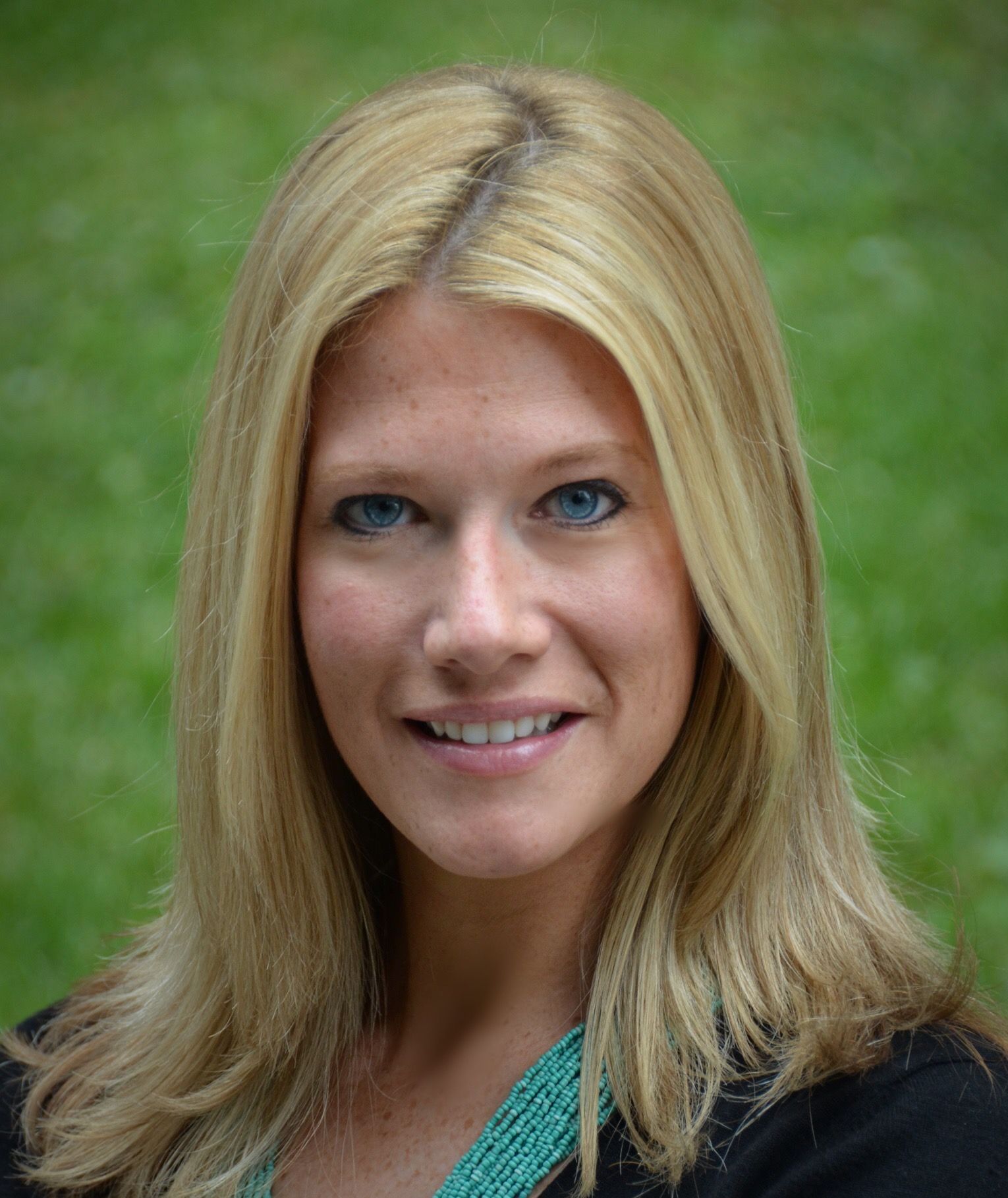 A woman with blonde hair and blue eyes is smiling for the camera.