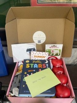 A custom patient care box filled with a book , candy canes , a dunkin ' donuts gift card , and other items.