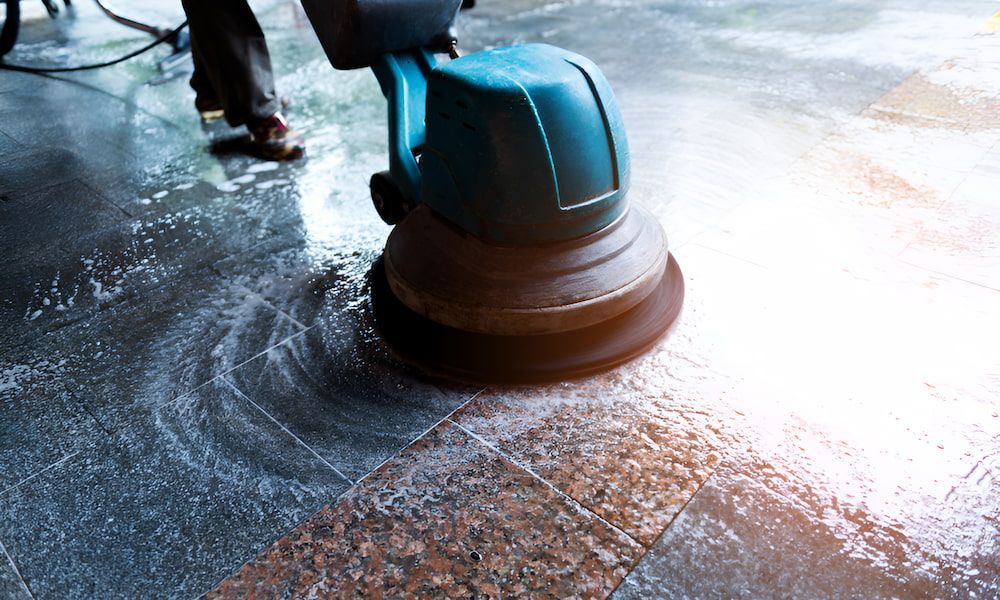 A Person Is Cleaning A Tiled Floor With A Machine — Kyall Chalker Floor Sanding & Polishing In Taree, NSW