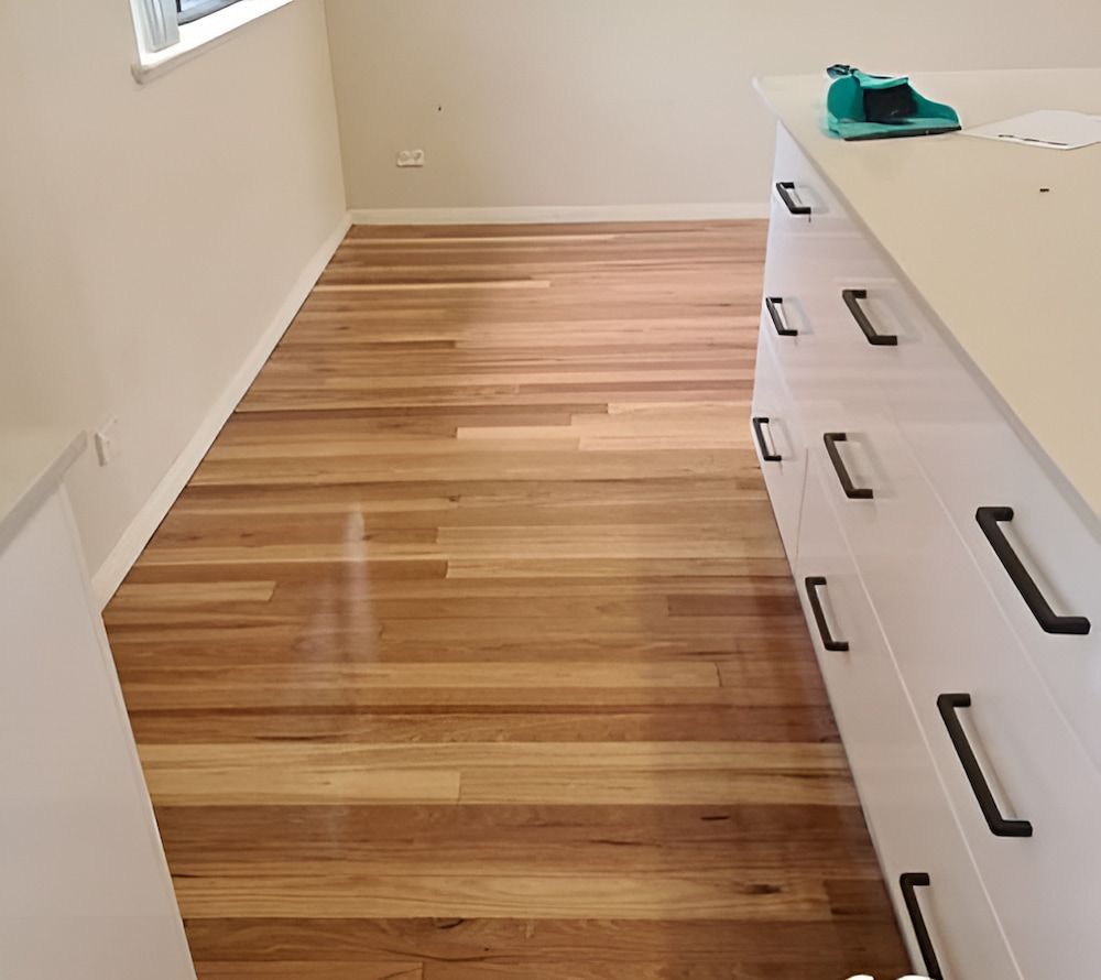 A Kitchen With Wooden Floors And White Cabinets — Kyall Chalker Floor Sanding & Polishing In Taree, NSW