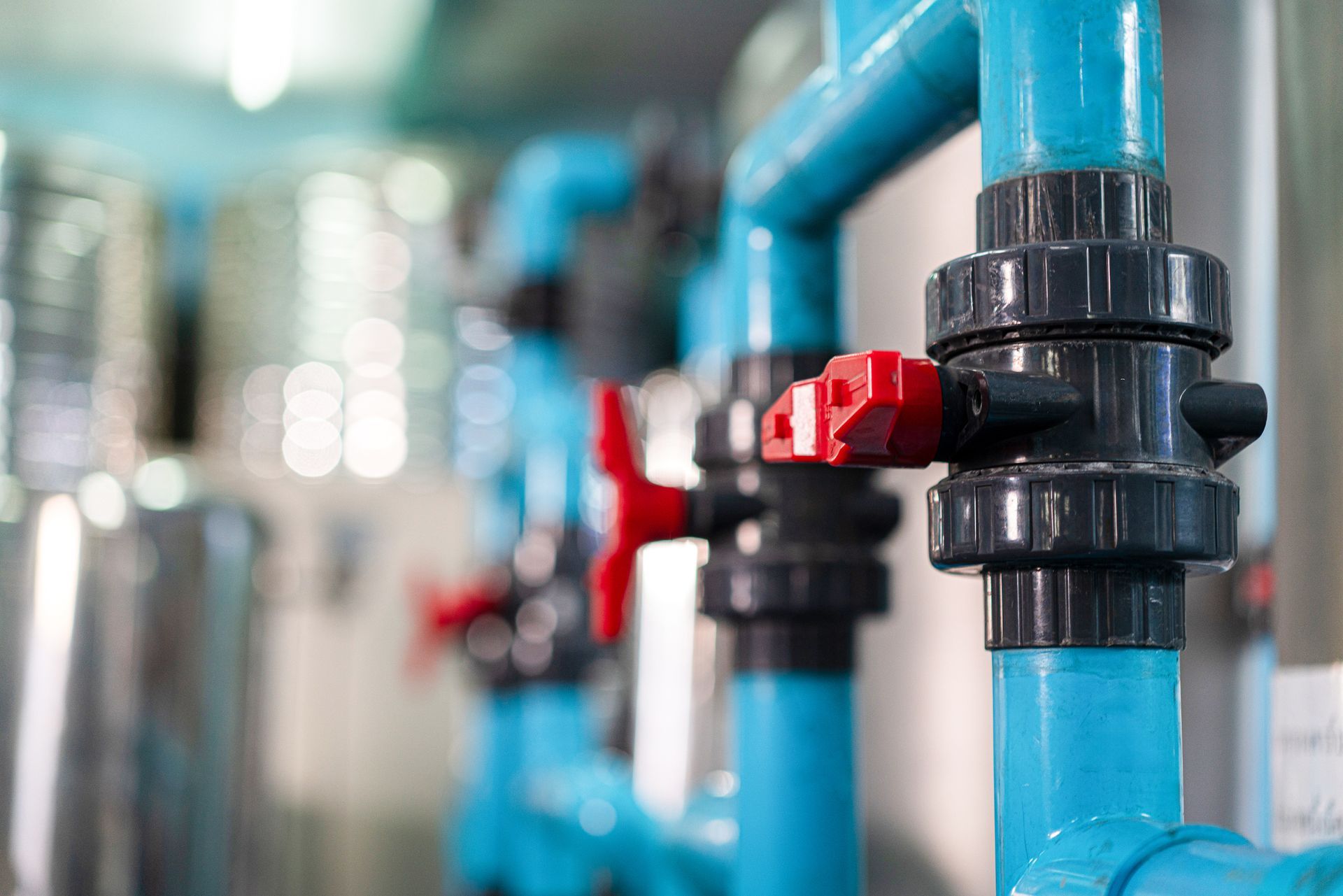 A row of blue pipes with red valves in a factory.