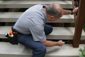 Mitch is kneeling down on a set of stairs while working on a railing.